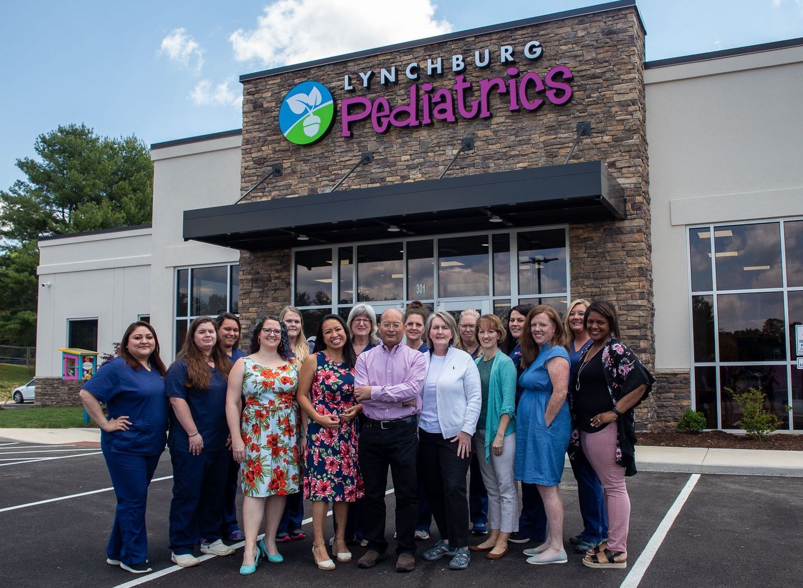 Staff members pose in front of the Lynchburg Pediatrics office building on a sunny day.