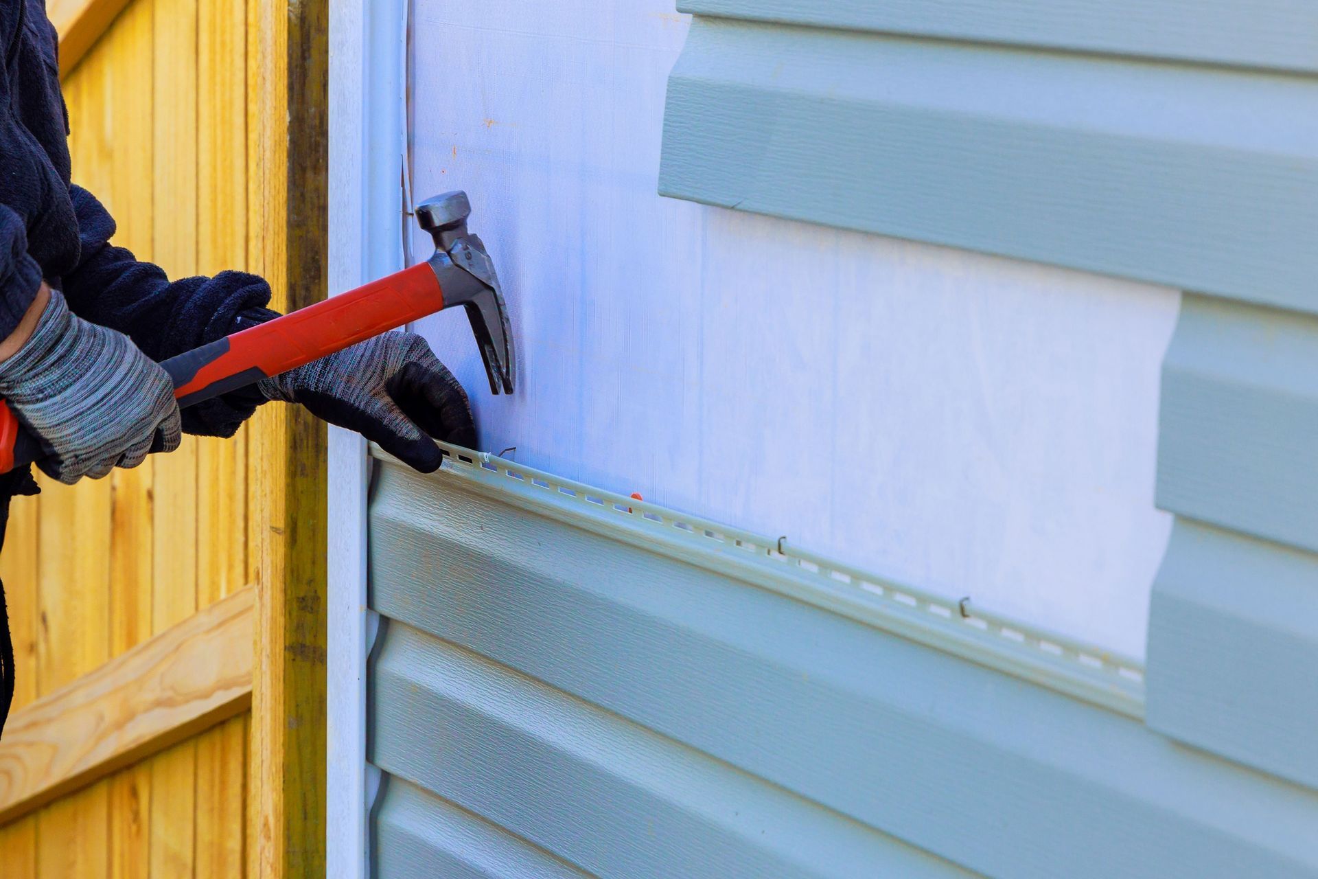 Close-up of a contractor performing siding repair on a house.
