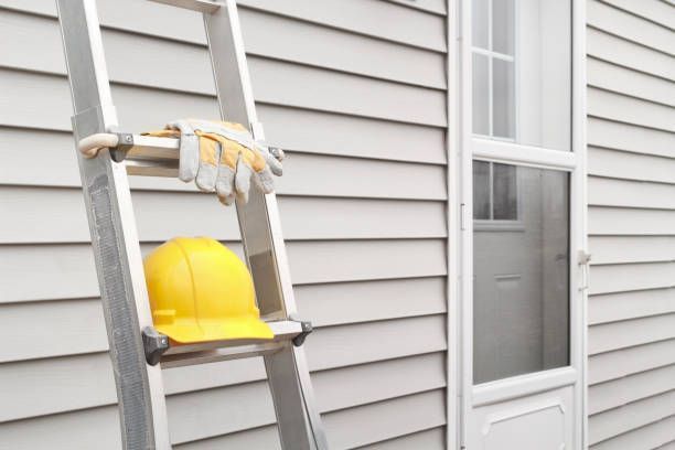 A ladder with a hard hat and gloves on it is leaning against a house.