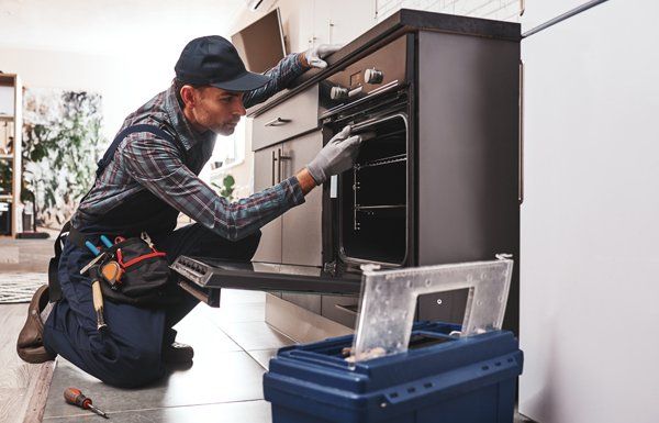 Close-Up of Repairman Examining Oven — Voorhees, NJ — Appliance Werks