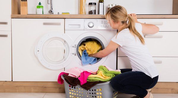 Woman Loading Clothes Into Washing Machine — Voorhees, NJ — Appliance Werks