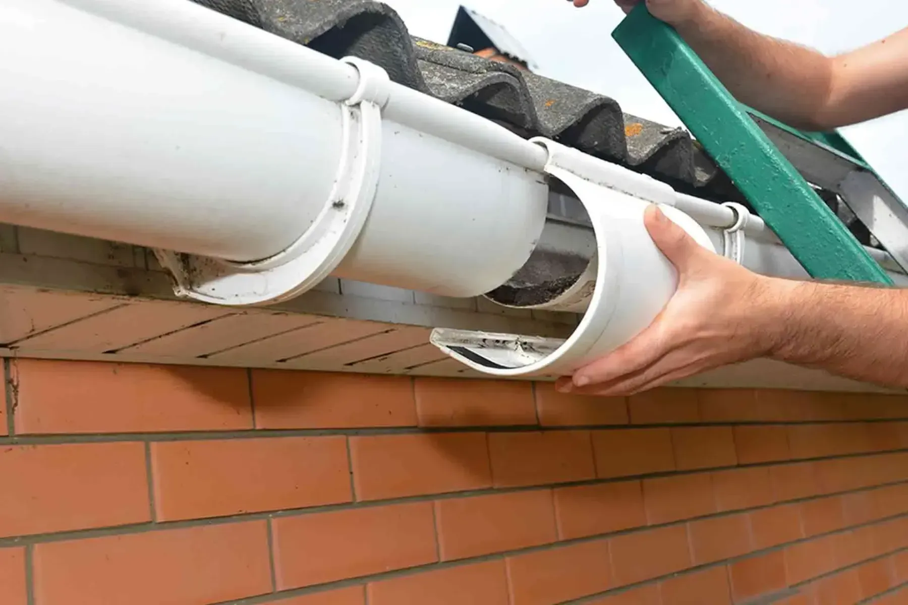 Hand snapping a white vinyl gutter section into a bracket.