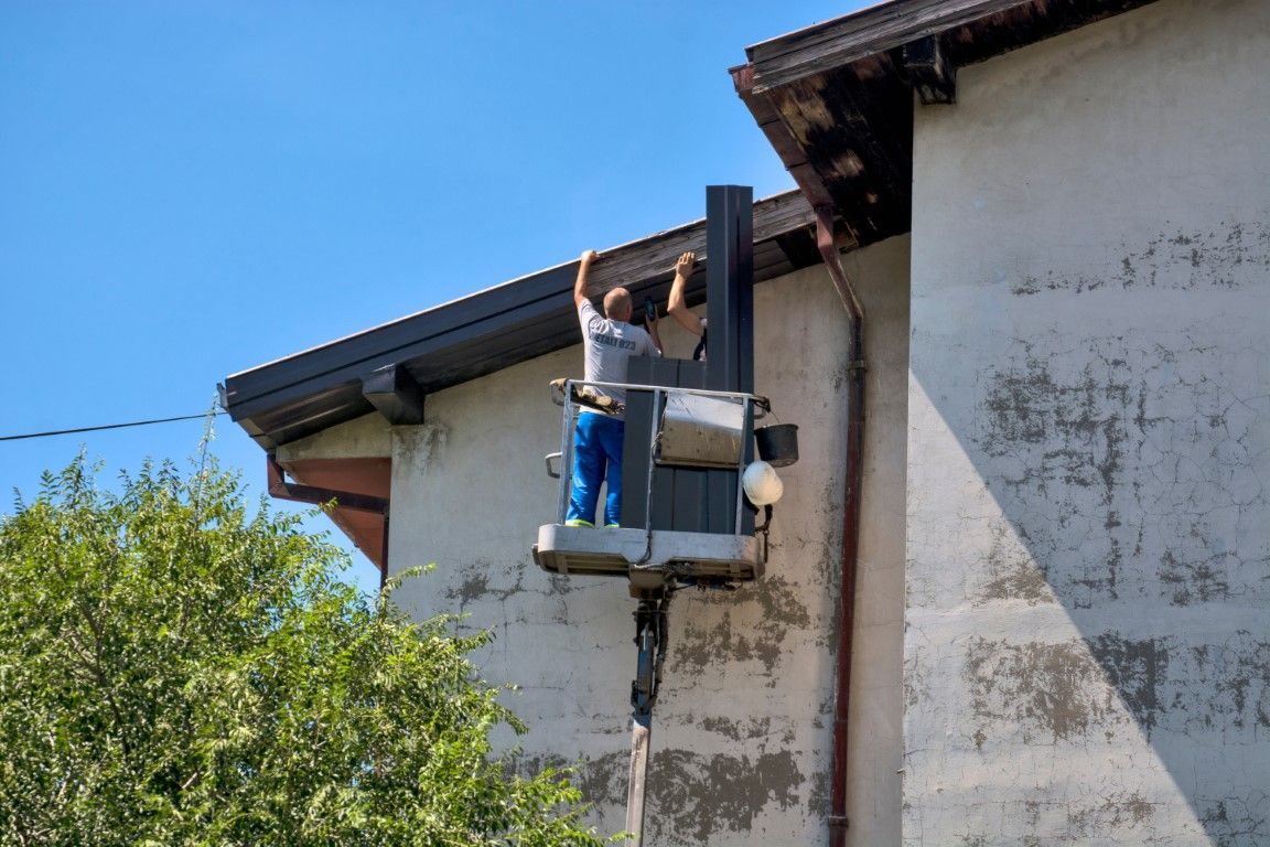 Professional cleaner on a ladder scrubbing home gutters.