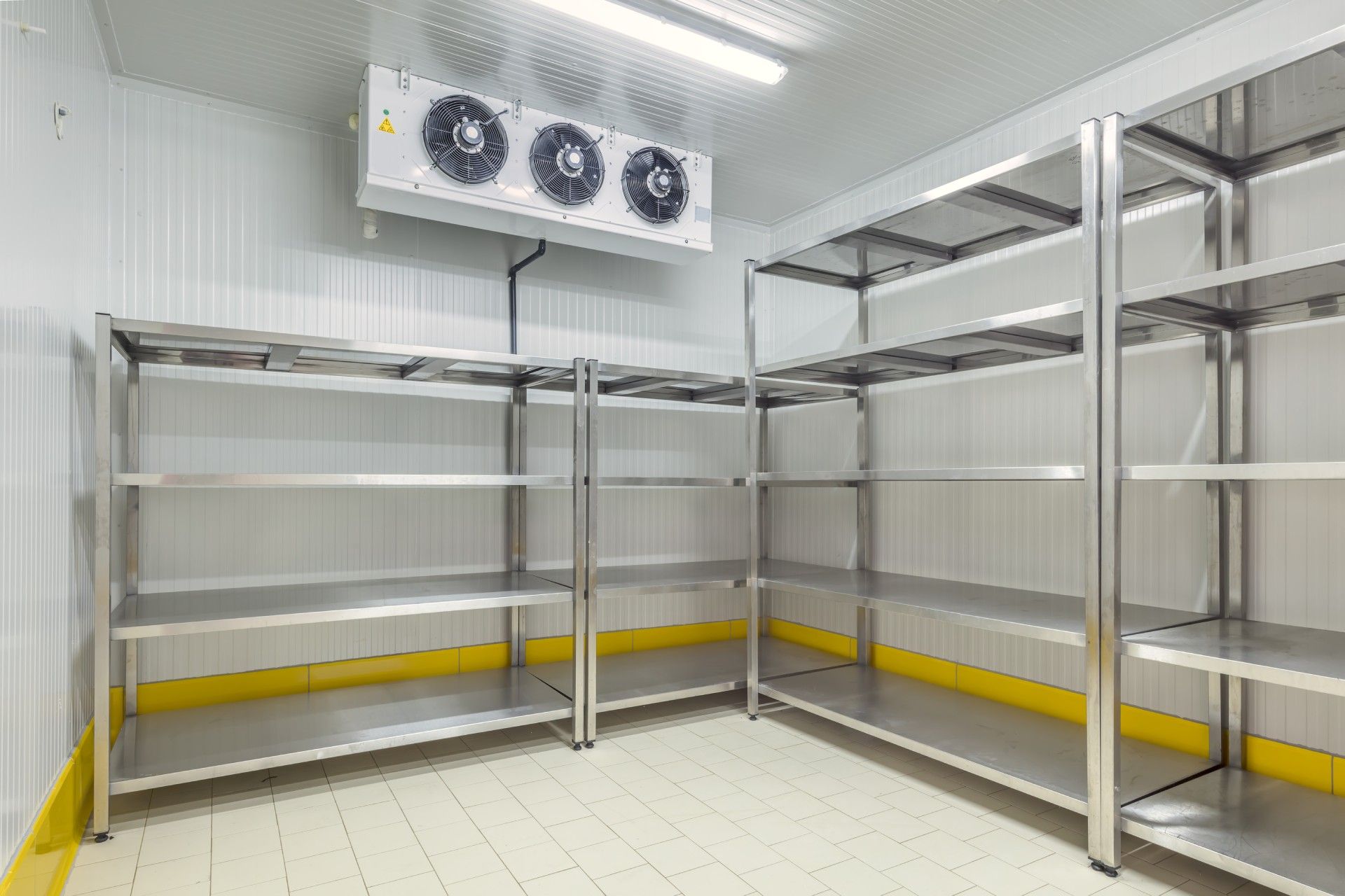 A room with stainless steel shelves and a refrigerator.