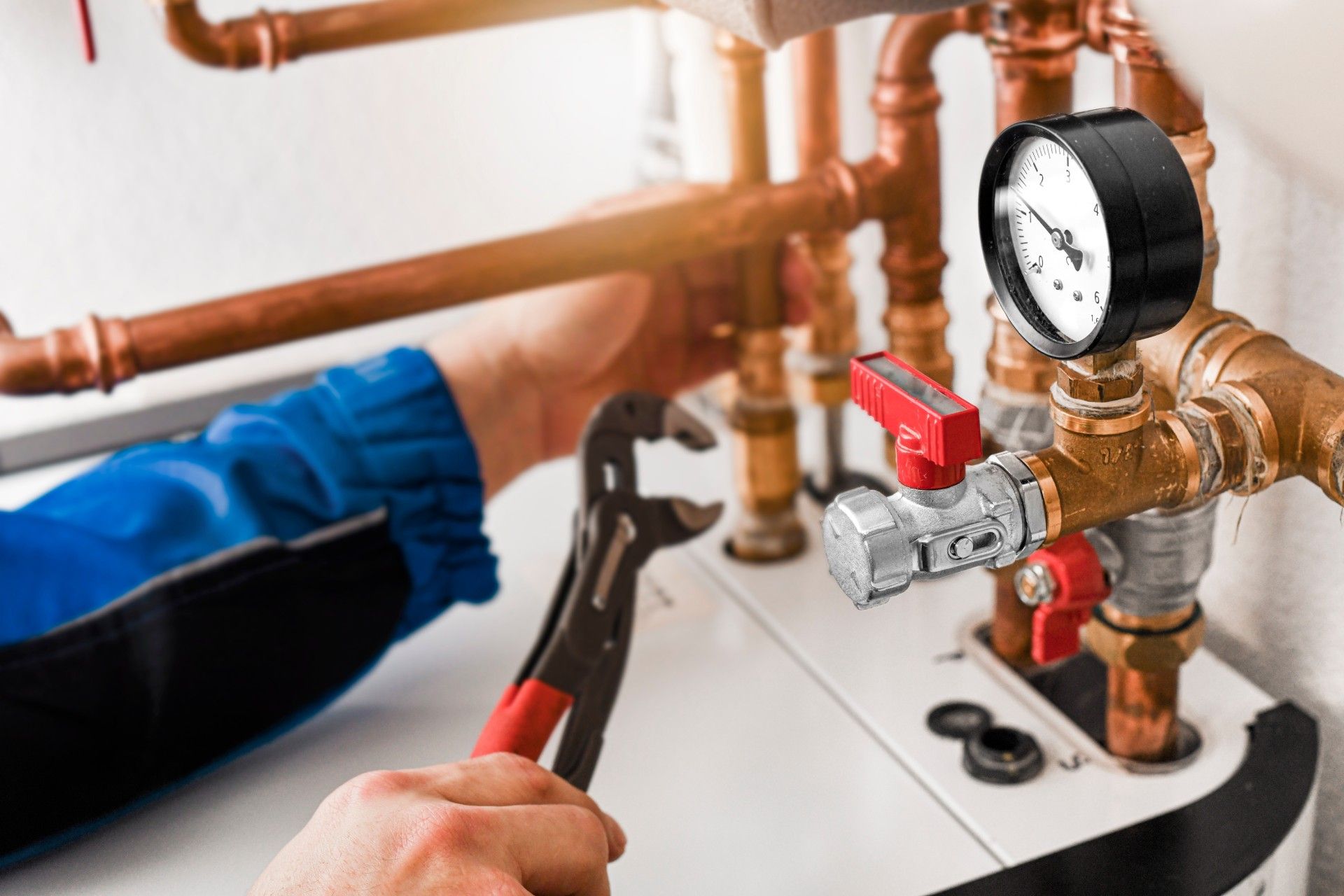 A plumber is working on a water heater with a wrench.