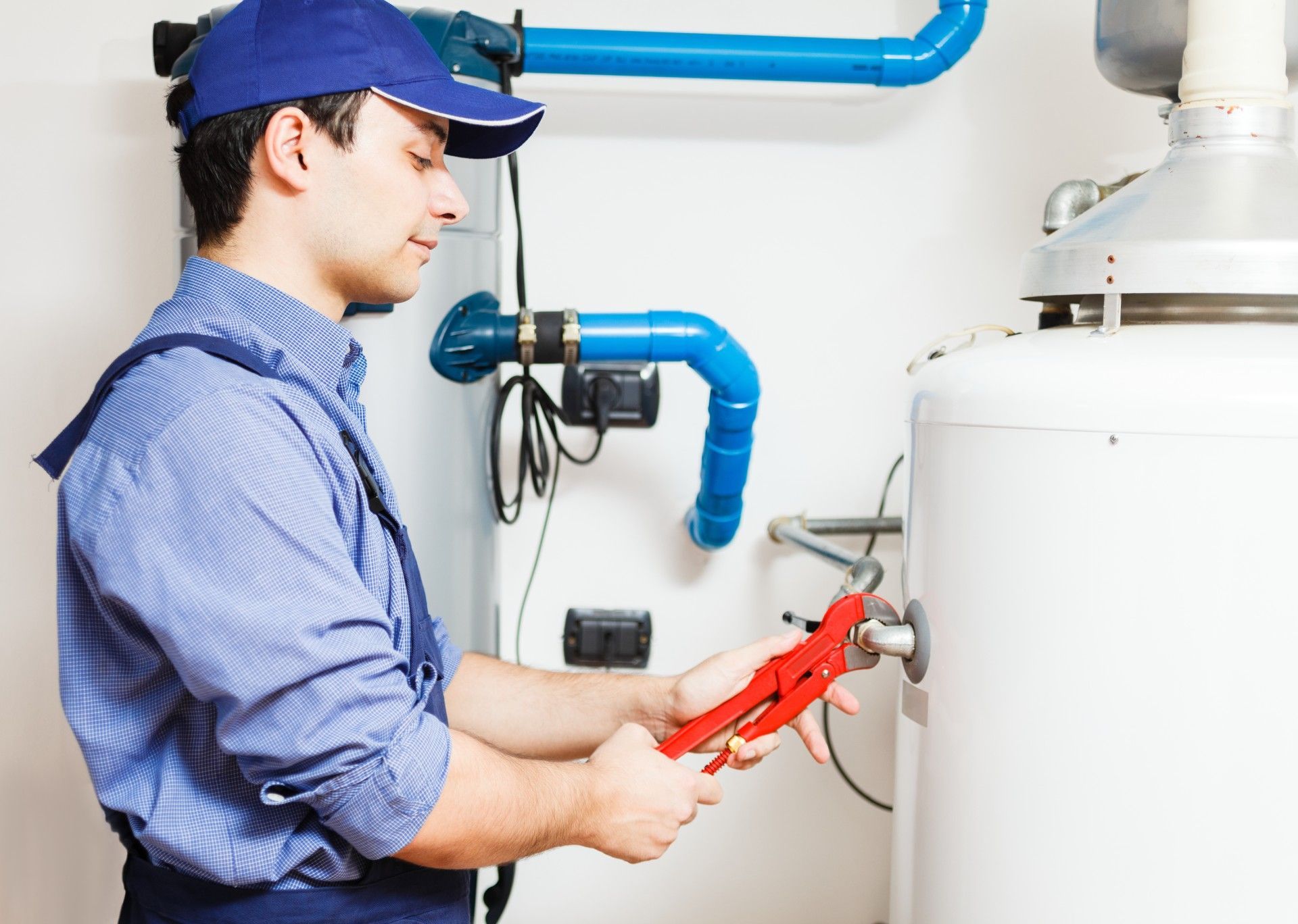 A man is fixing a water heater with a wrench.