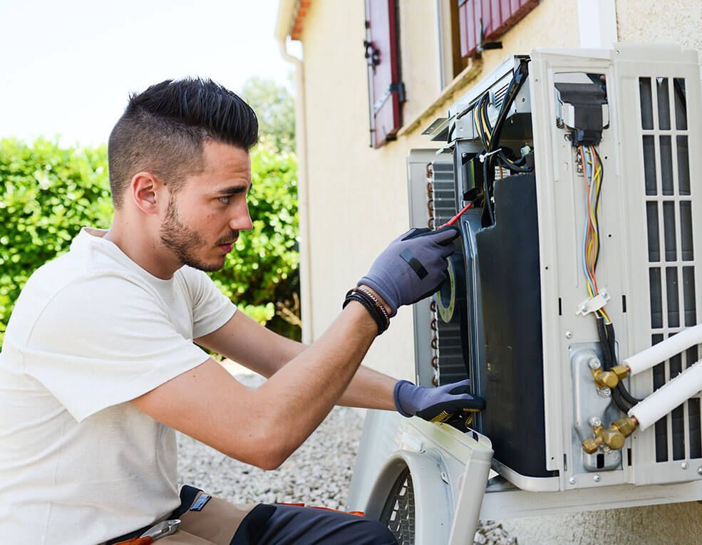 A man is working on an air conditioner outside of a house.