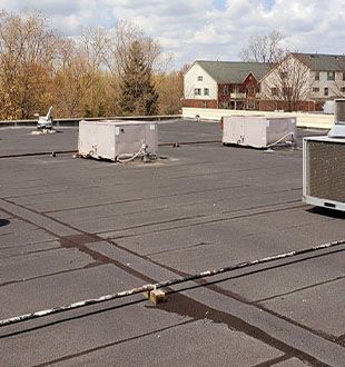 A roof with a lot of boxes on it and a building in the background.