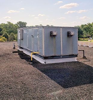 A large gray box is sitting on top of a gravel roof.