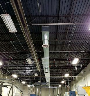 A large warehouse with a lot of pipes hanging from the ceiling.