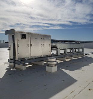 A large metal box is sitting on top of a white roof.