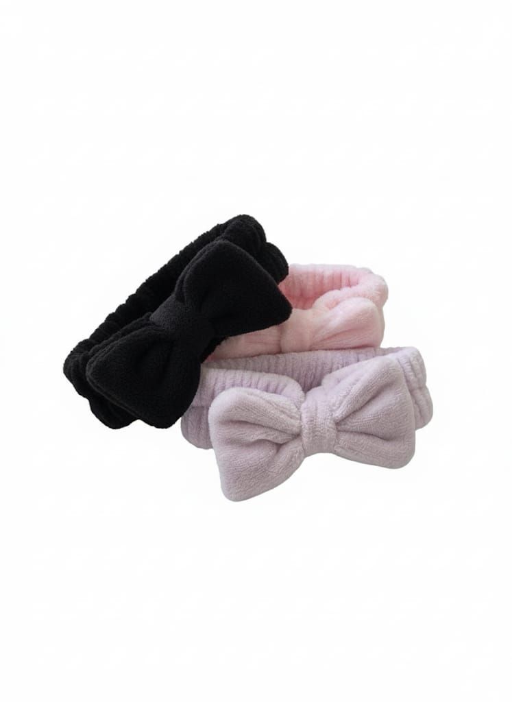 Tres diademas con lazos esponjosos apiladas: negra, rosa y lavanda.
