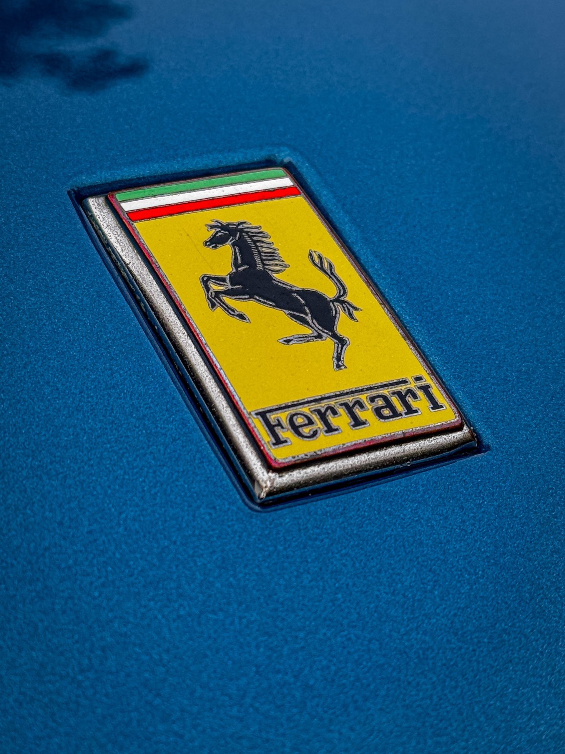 Een close-up van een Ferrari-logo op een blauwe auto