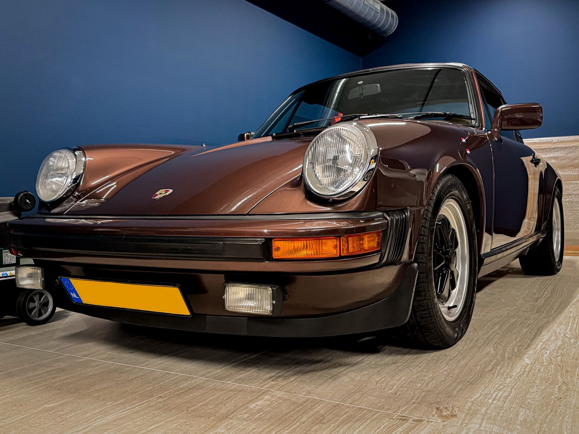 Een bruine Porsche staat geparkeerd in een garage.