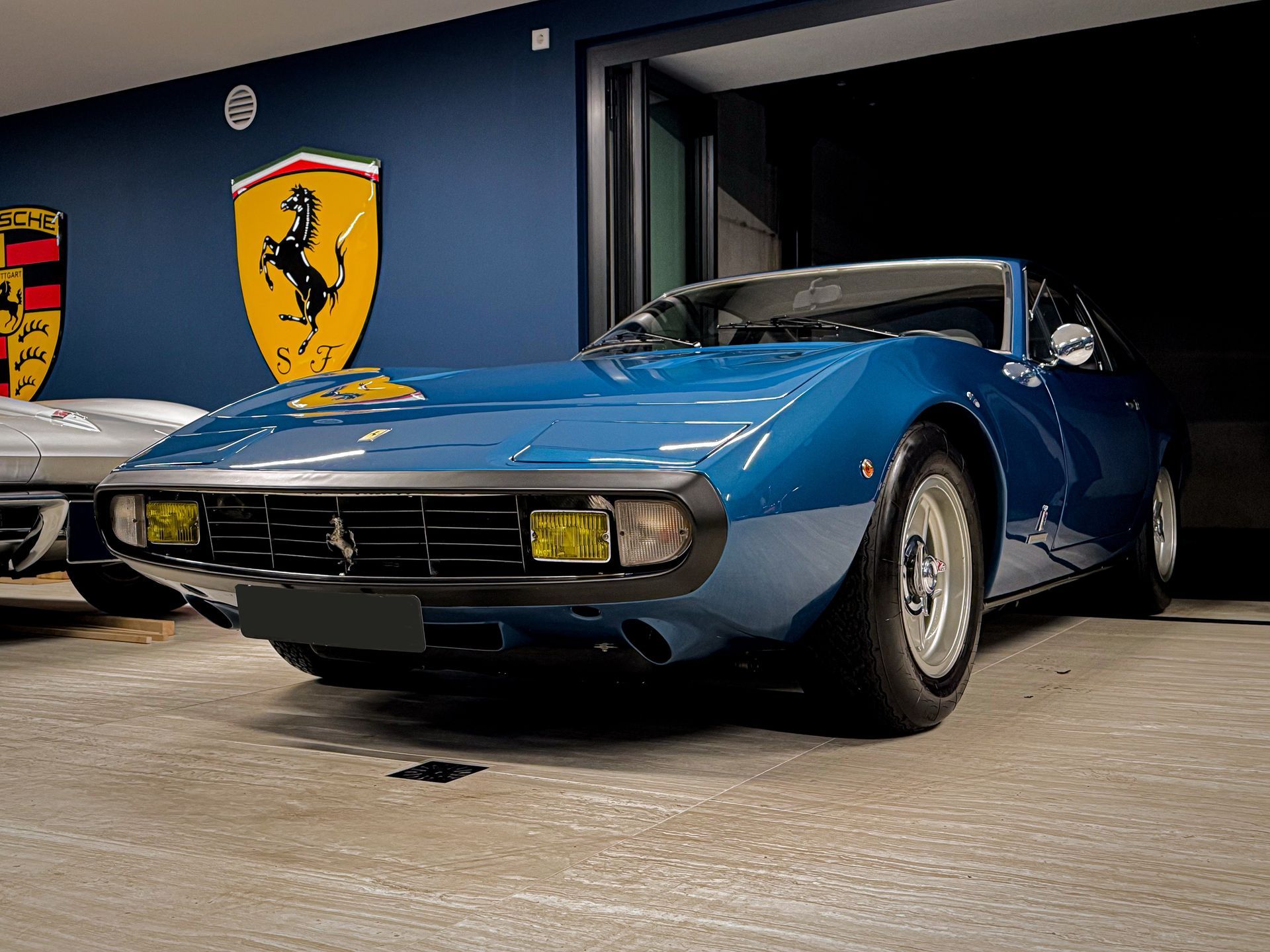 Een blauwe Ferrari sportwagen staat geparkeerd in een garage.