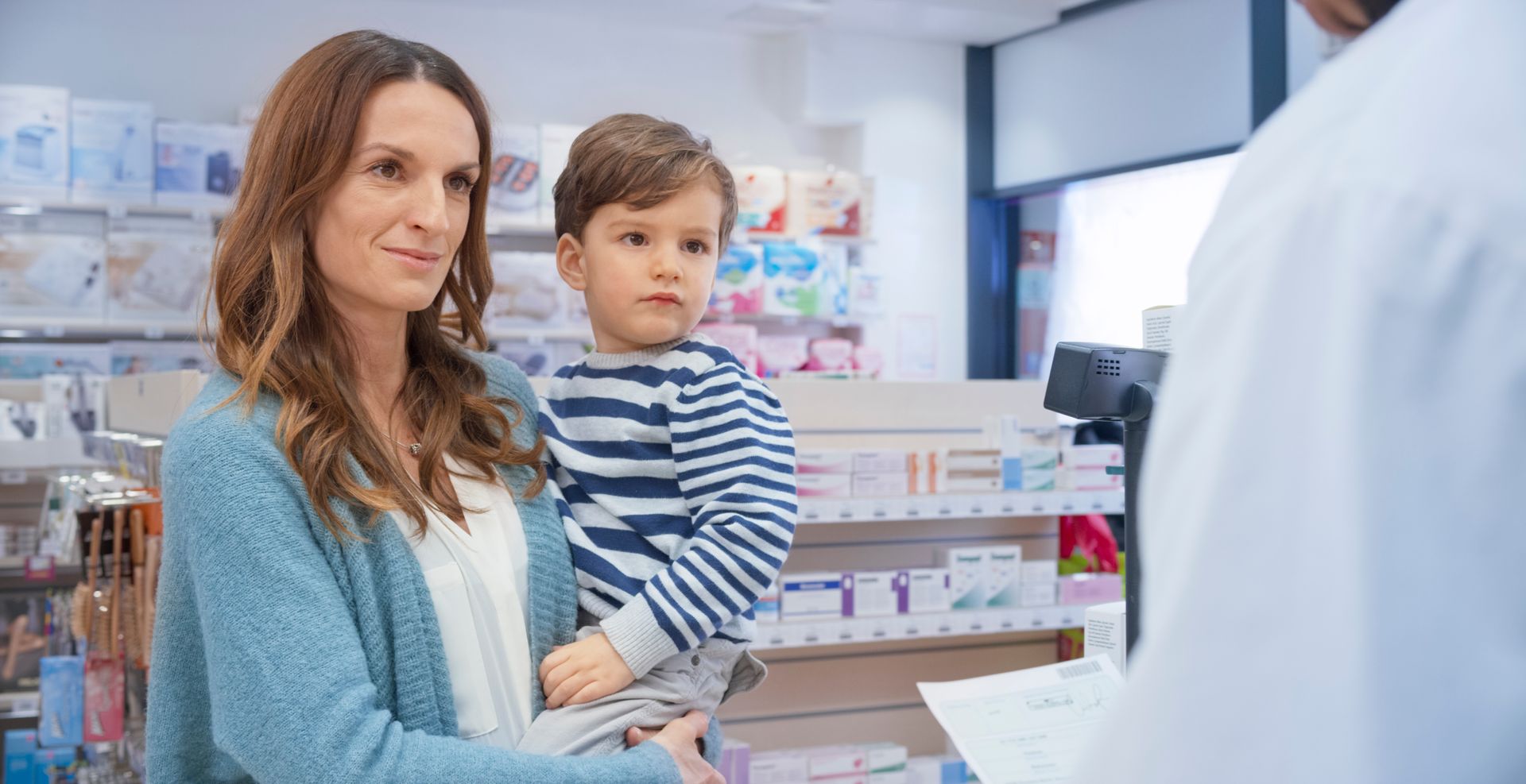 Una donna tiene in braccio un bambino in una farmacia.