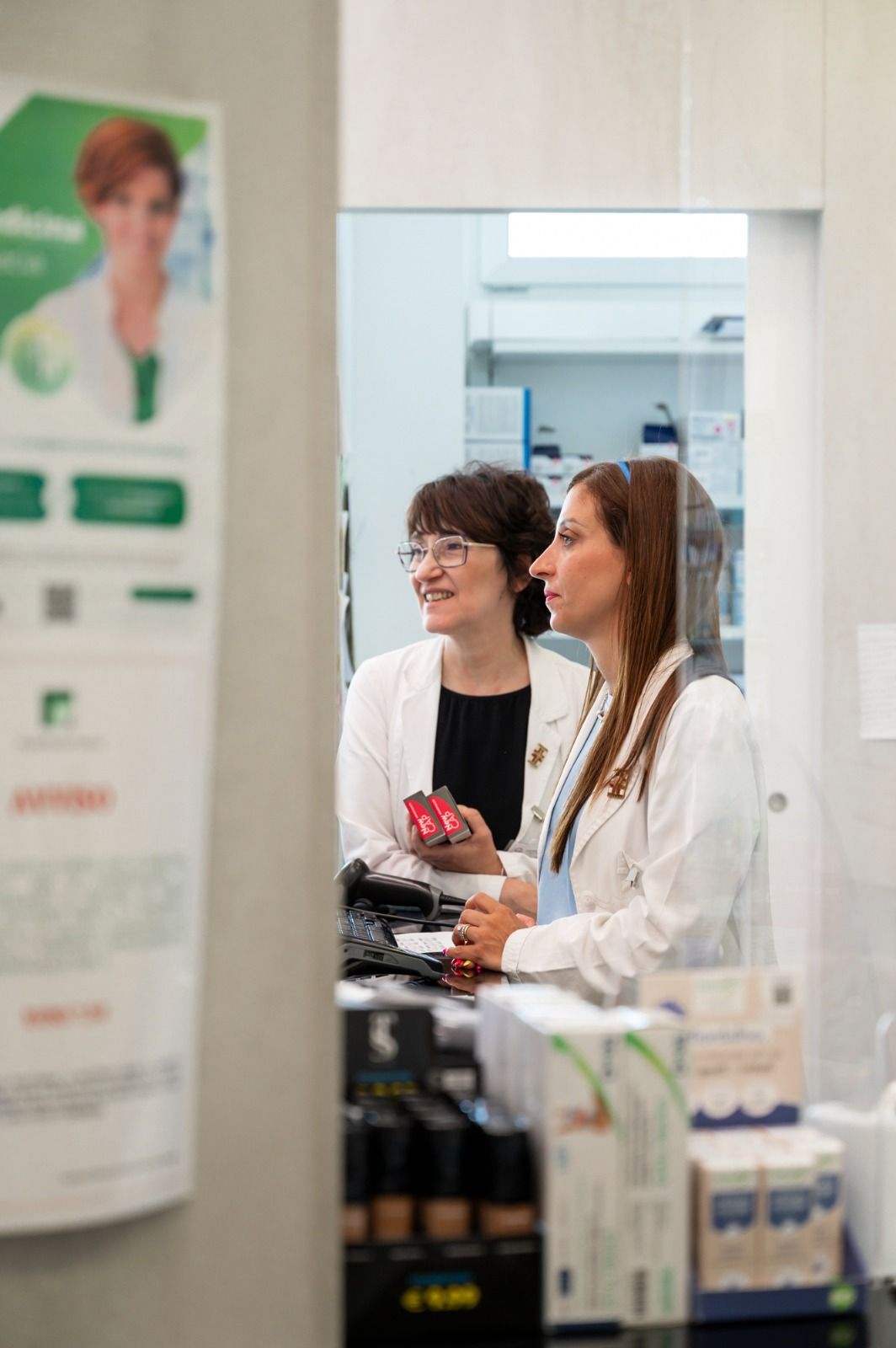 Due farmaciste sono in piedi in una farmacia e parlano tra loro.