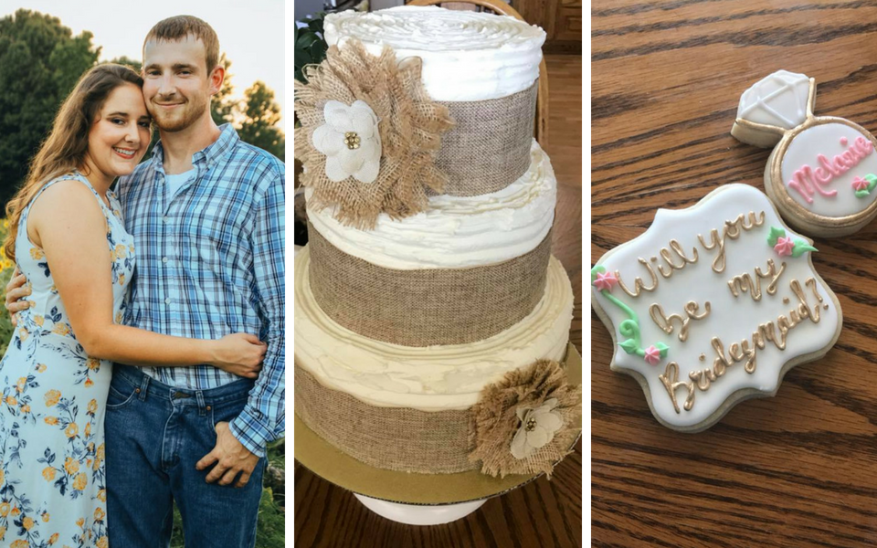 Couple posing beside a rustic cake and decorated cookies on a wooden table