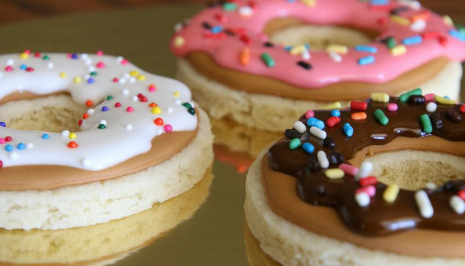 Three frosted donuts with colorful sprinkles on a tray