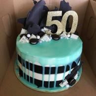50th birthday cake with teal frosting, gold “50” topper, and black-and-white decorations