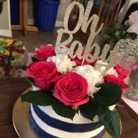 Red and white roses on a striped cake topped with “Oh Baby” decoration