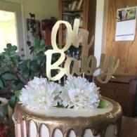 Baby shower cake with gold topper and white flowers indoors