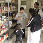 People at a food bank, selecting items from shelves stocked with canned goods and other groceries.