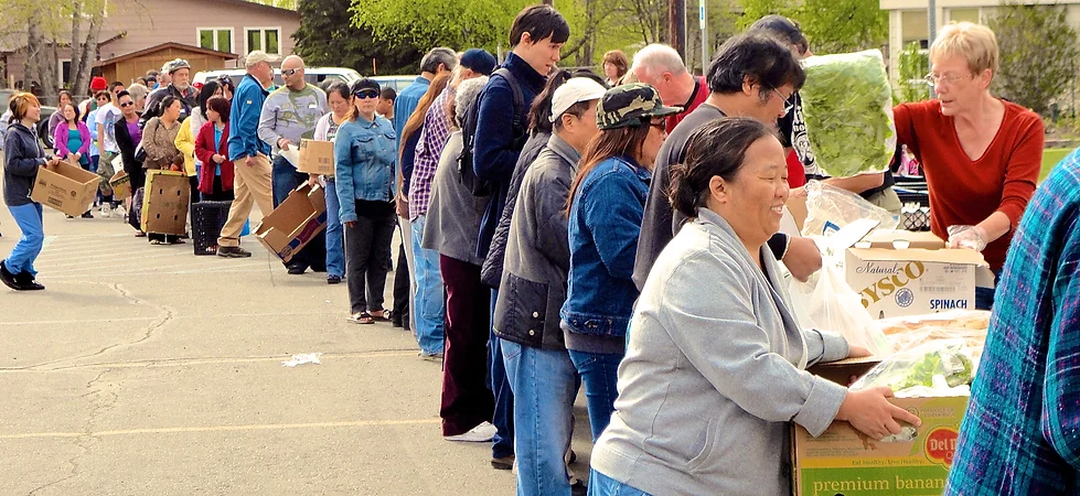 People waiting in line to receive food boxes outdoors.