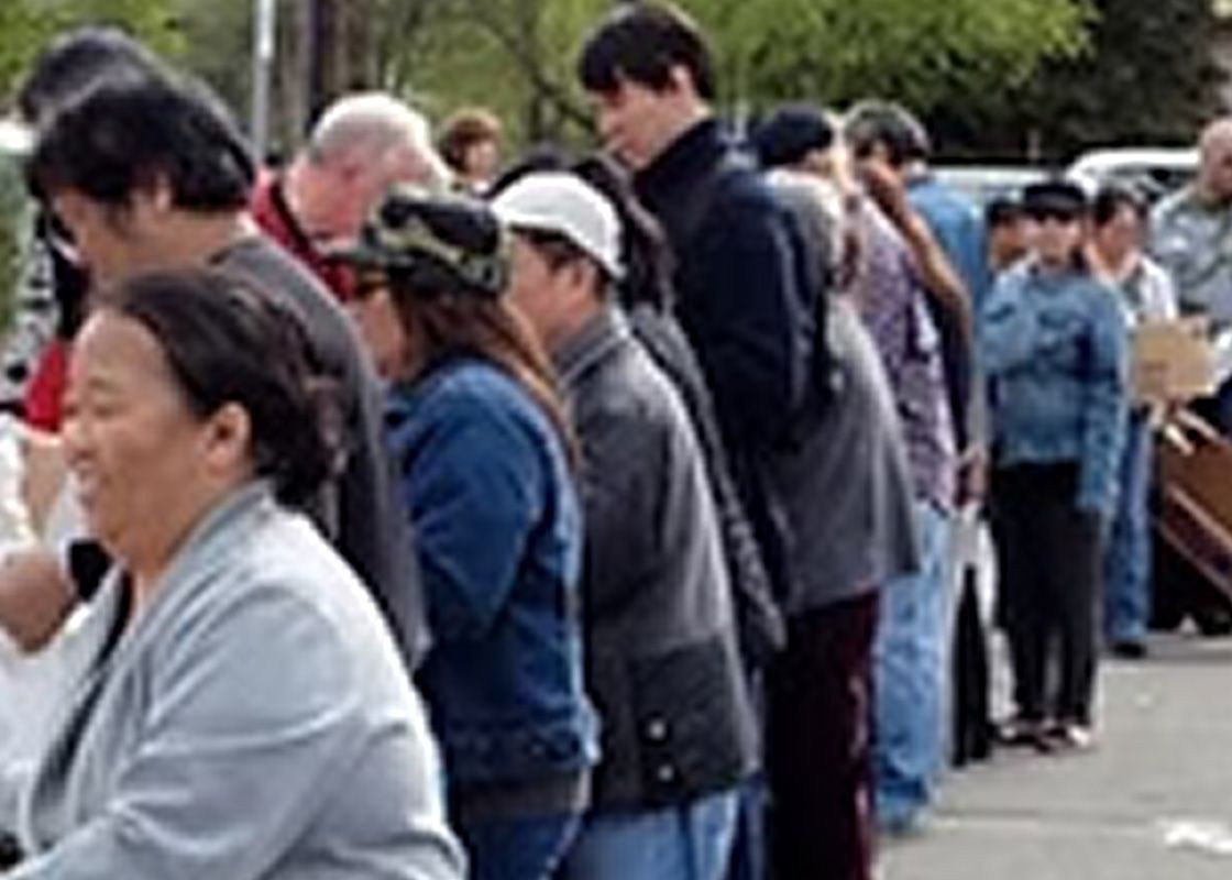 People standing in line outside, some wearing jackets.