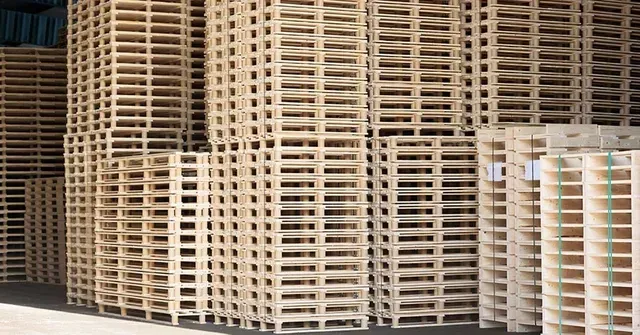 Stacks of wooden pallets in a warehouse setting.