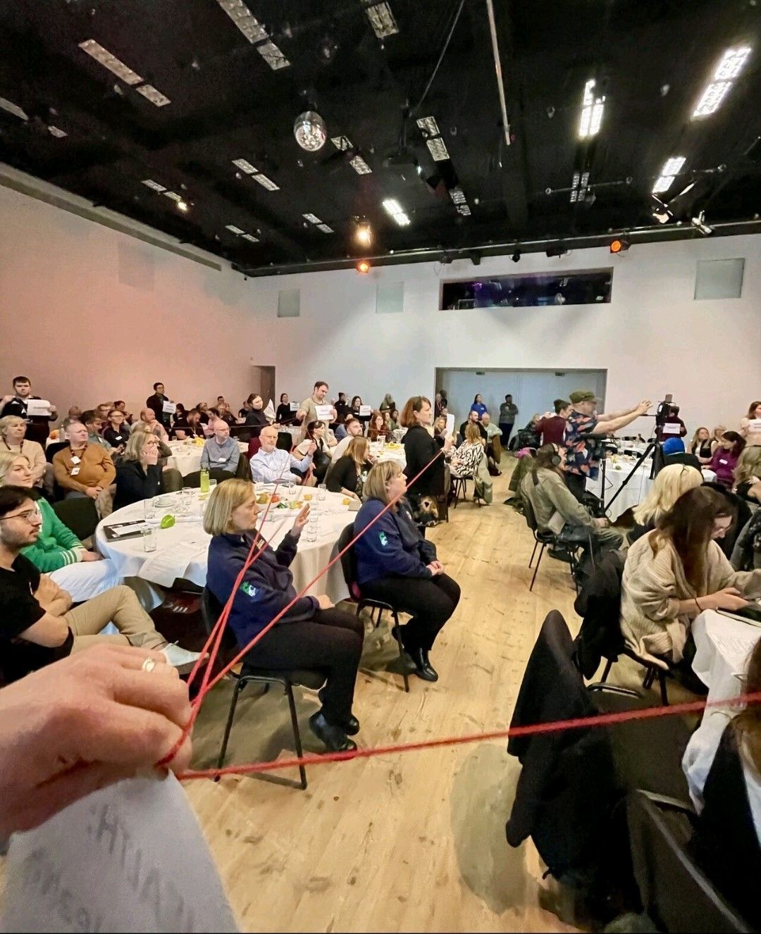 A large group of people are sitting at tables in a large room.