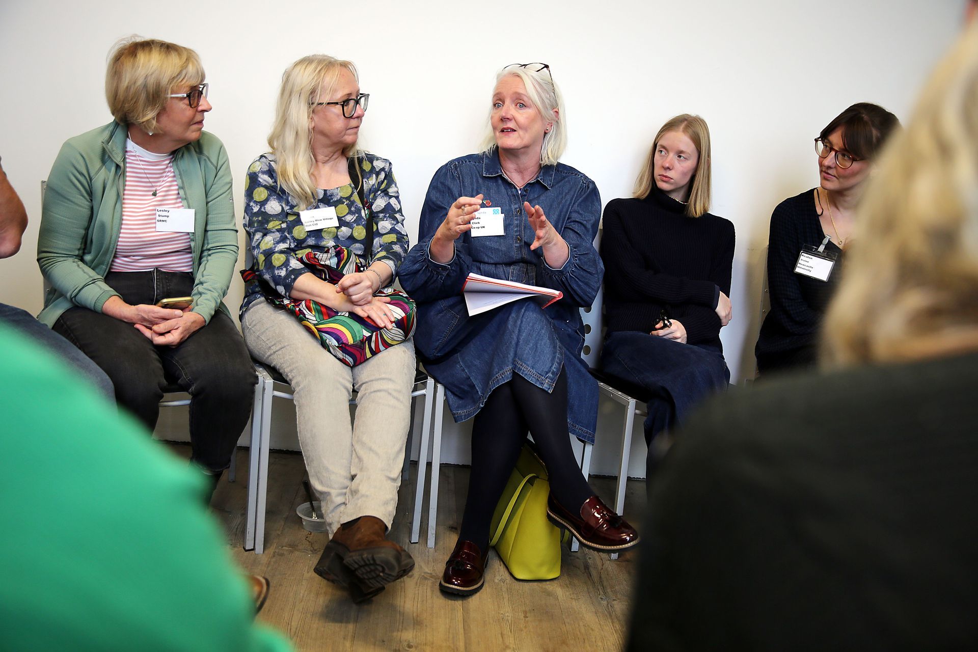 A group of women are sitting in a circle talking to each other.