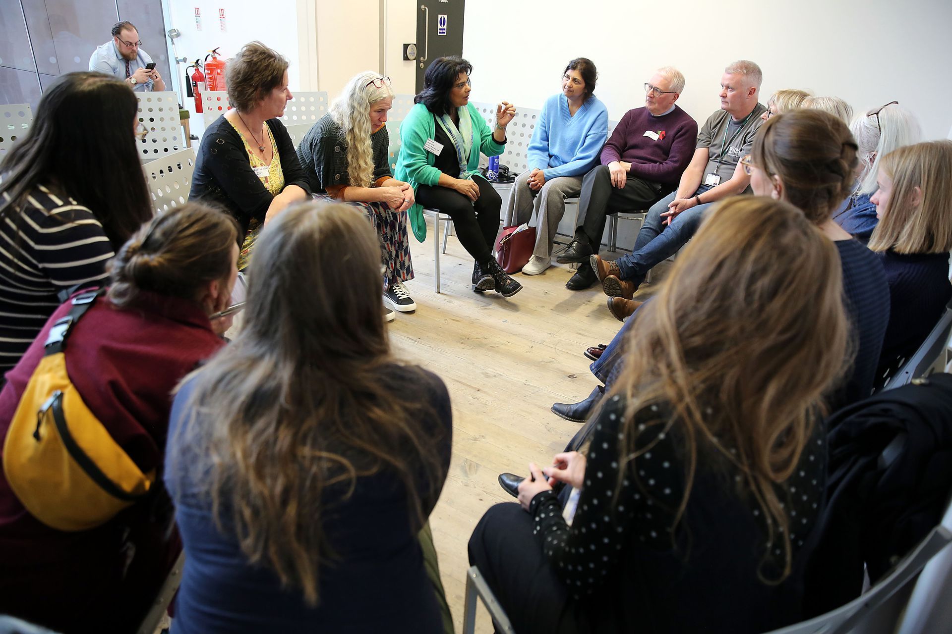A group of people are sitting in a circle talking to each other.