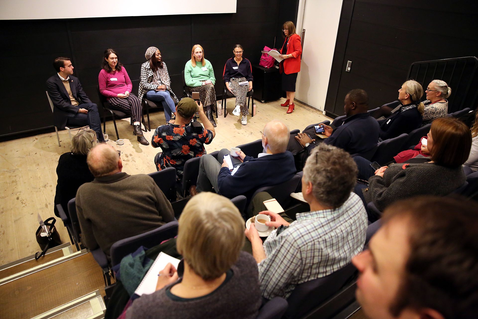 A group of people are sitting in a circle in an auditorium.