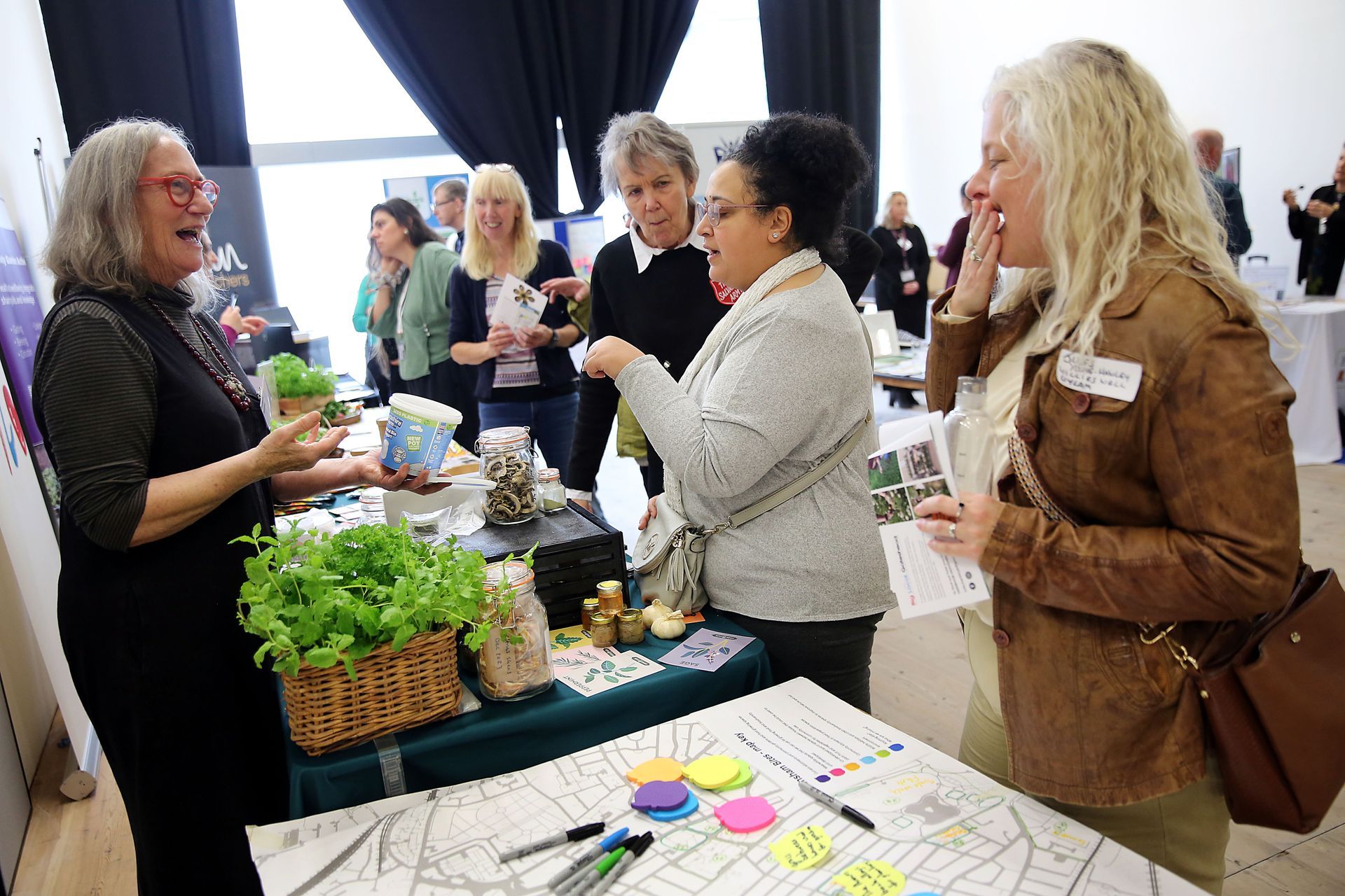 A group of women are standing around a table talking to each other.