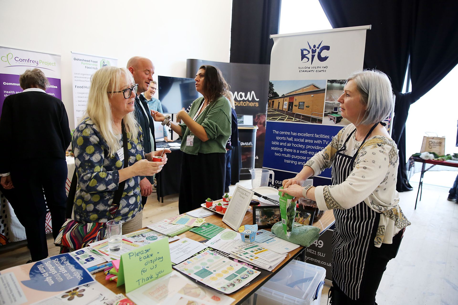 A group of people are standing around a table at a convention.