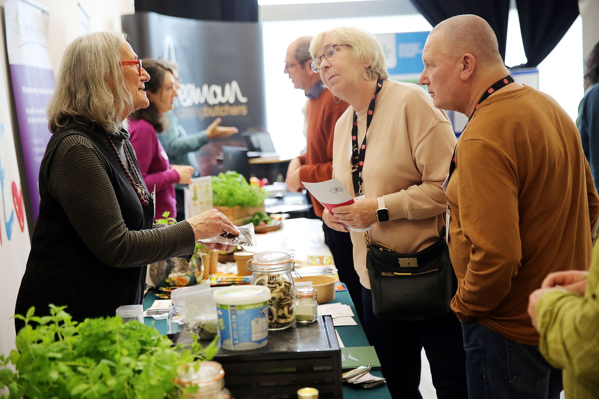 A group of people are standing around a table talking to each other.
