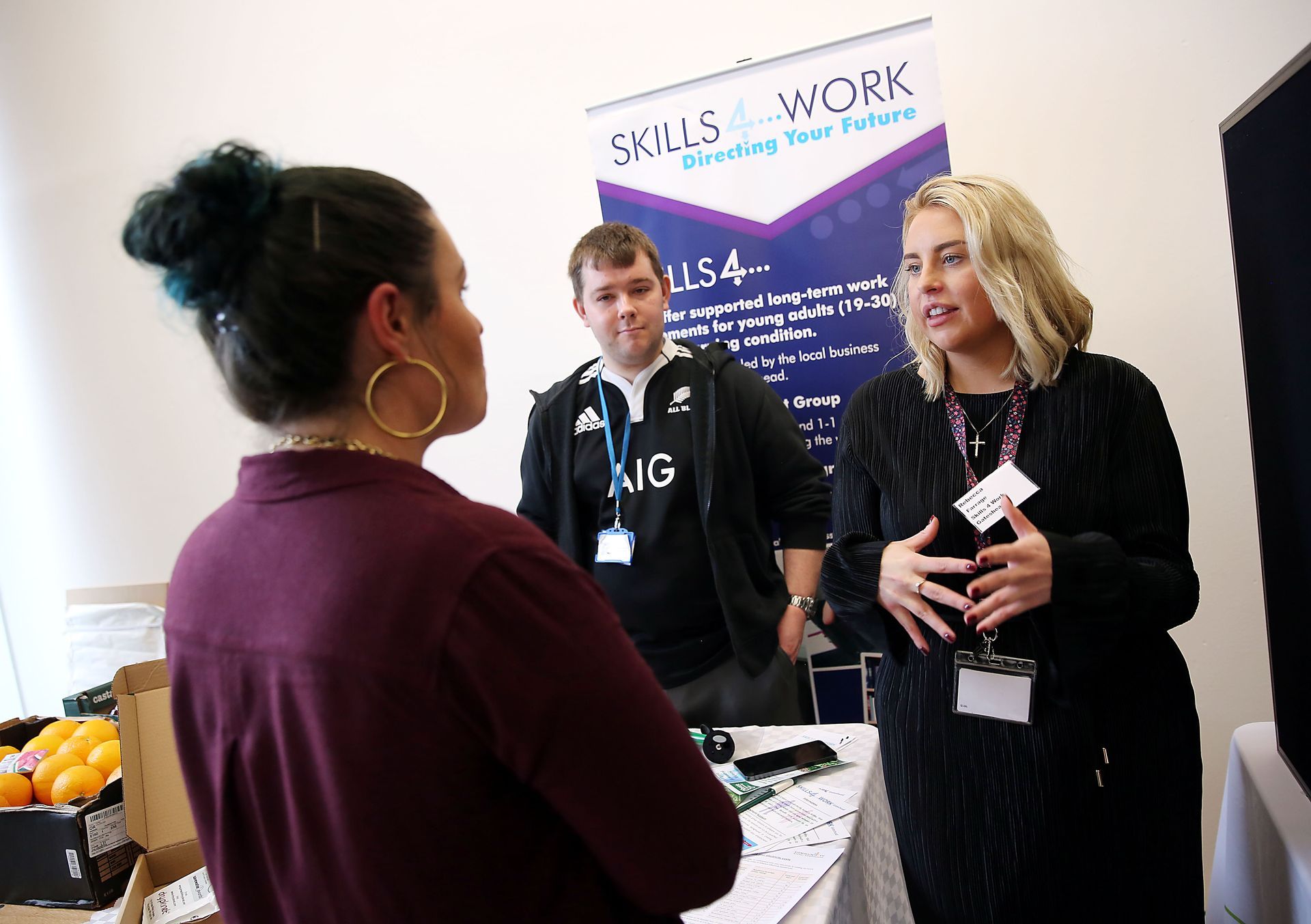 A group of people are standing around a table talking to each other.