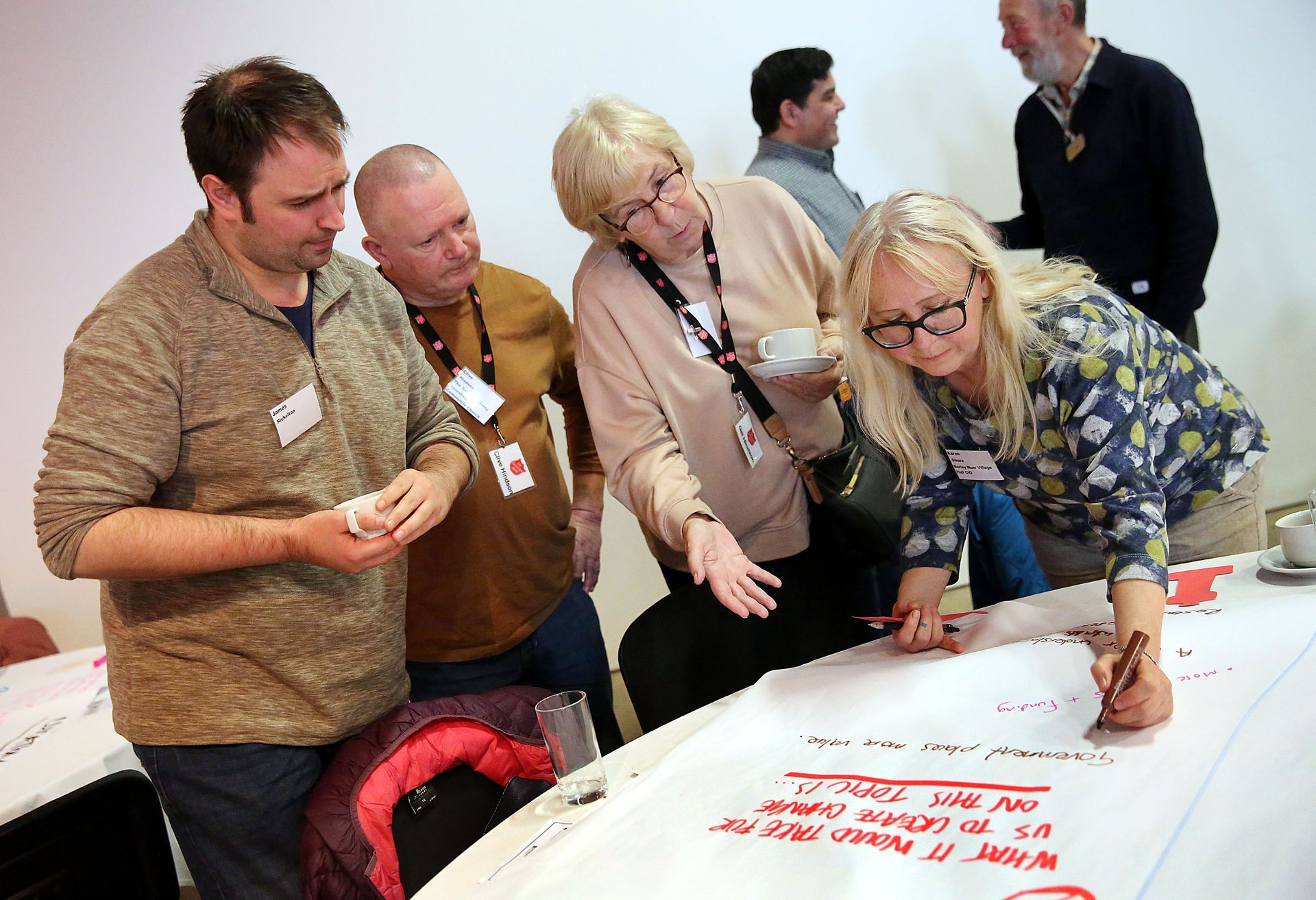 A group of people are sitting around a table writing on a piece of paper