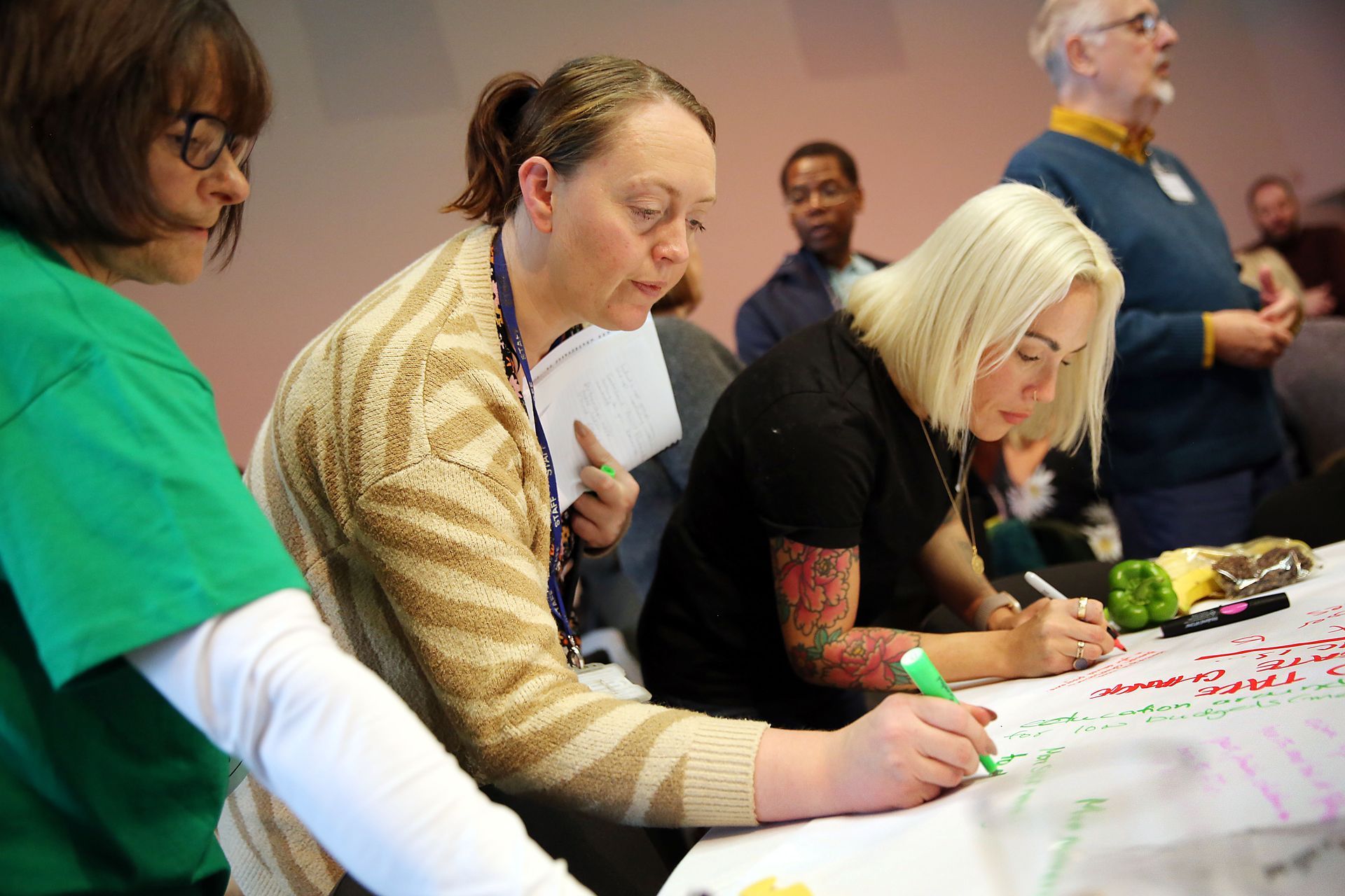 A group of people are sitting at a table writing on a piece of paper