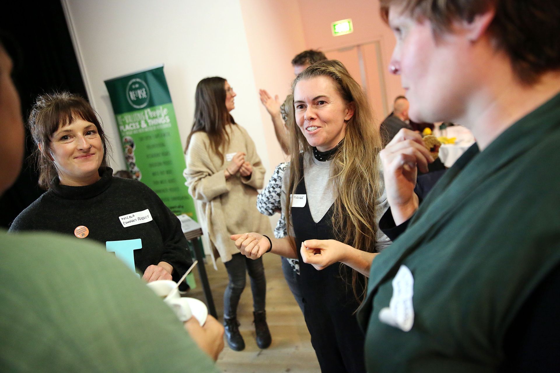 A group of people are standing in a room talking to each other.