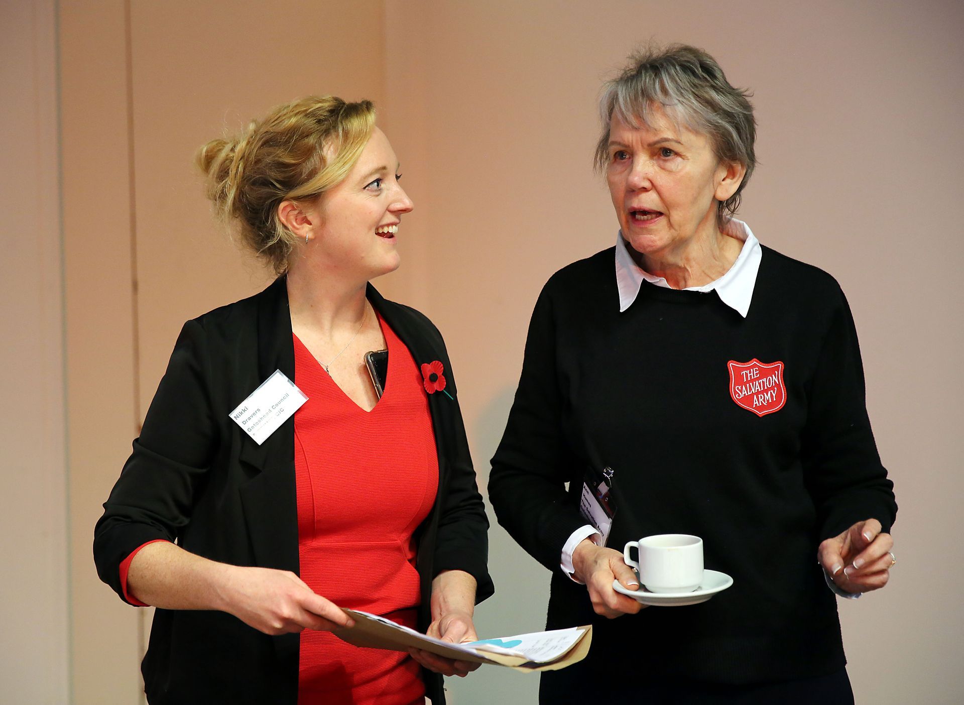 Two women are standing next to each other and one is holding a cup of coffee