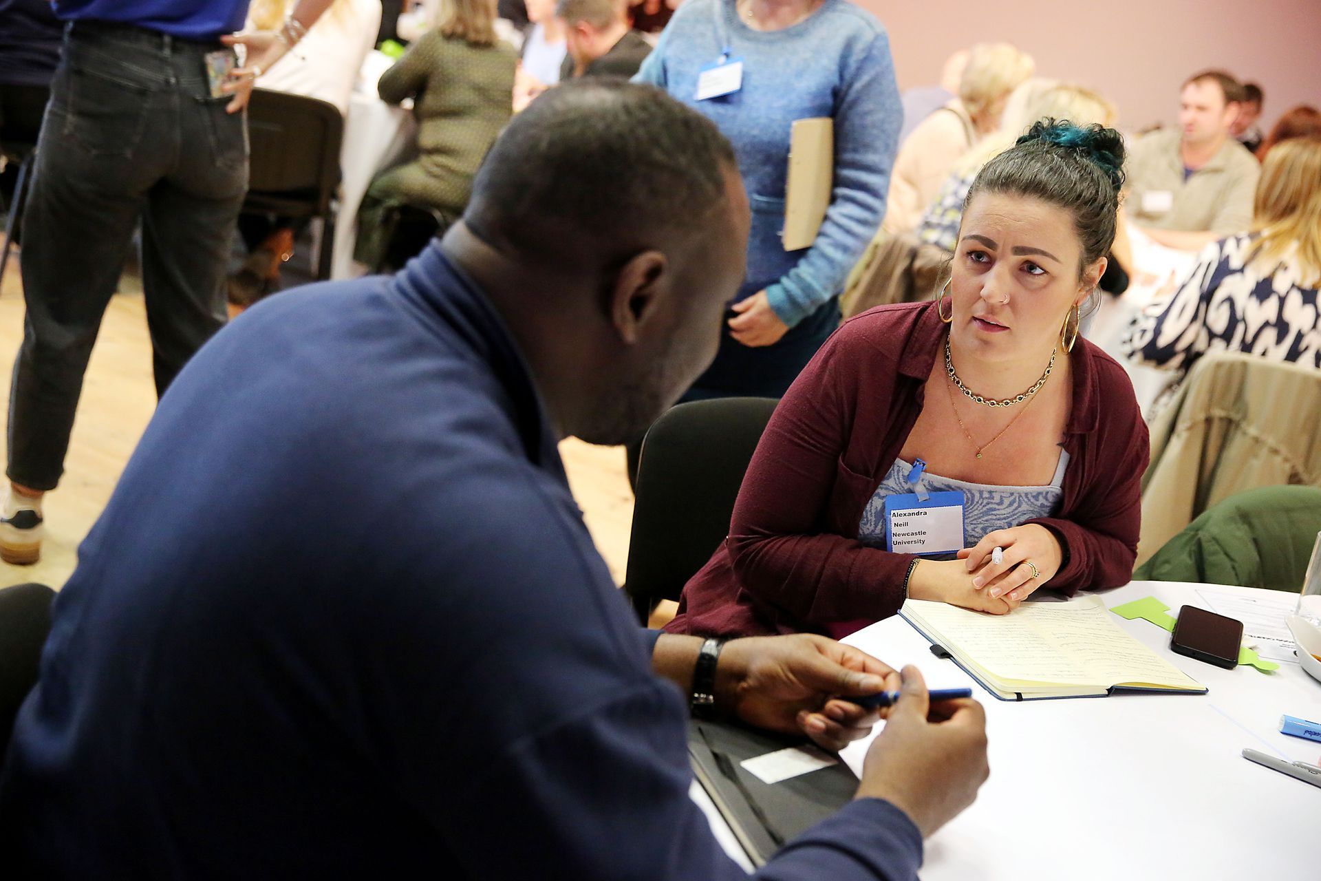 A man and a woman are sitting at a table talking to each other