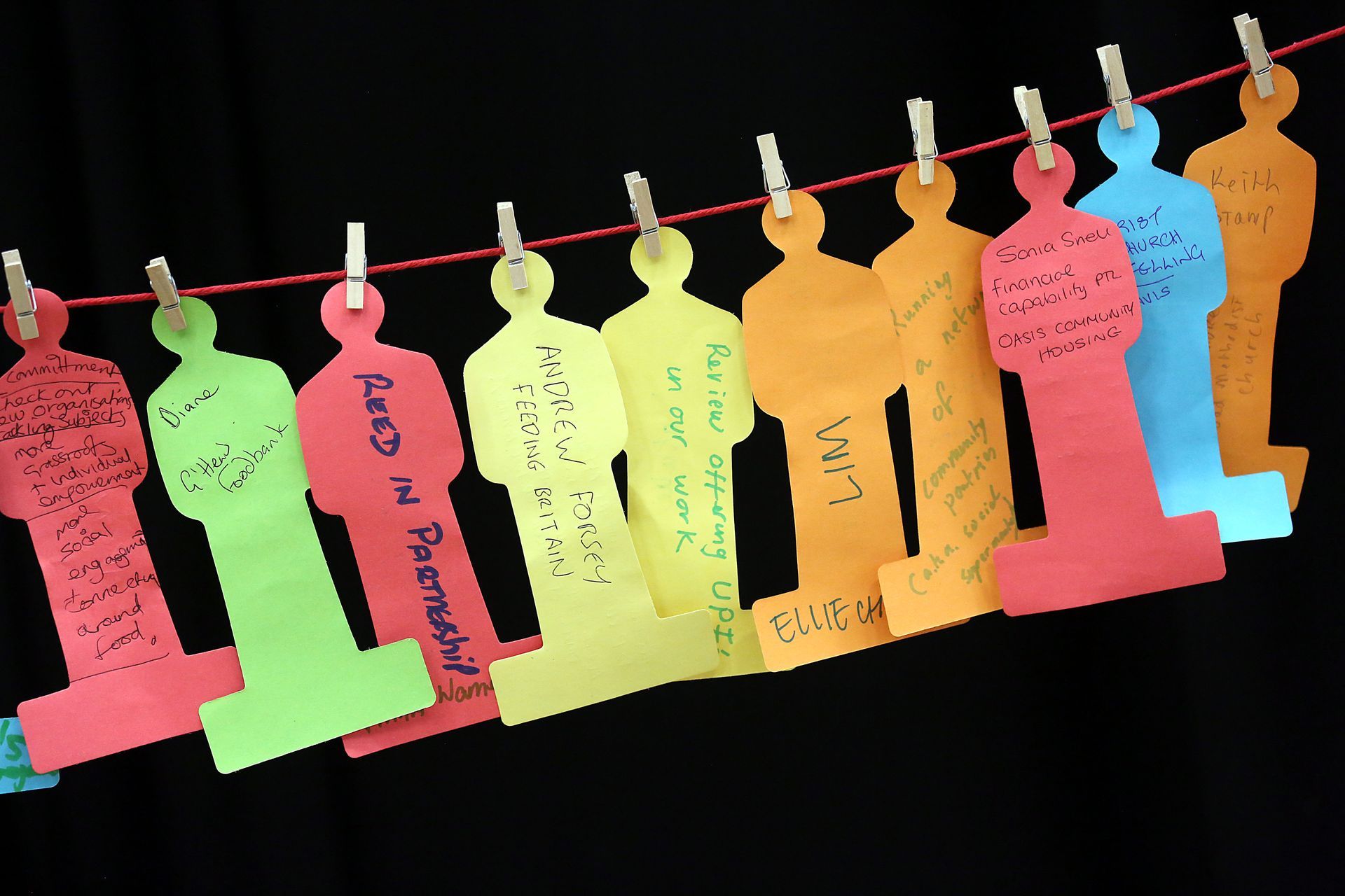 A row of colorful paper people hanging on a clothes line