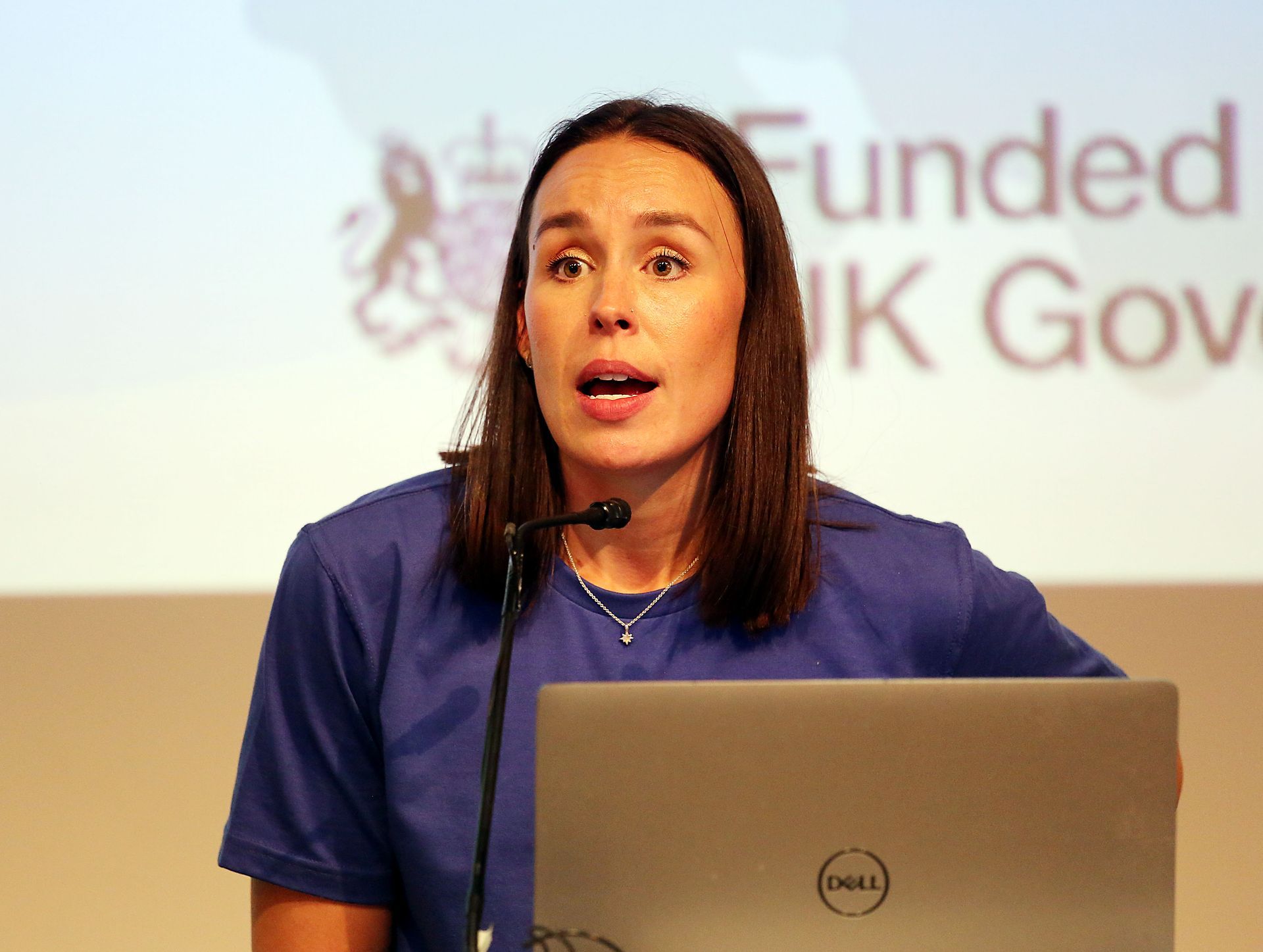 A woman is giving a speech in front of a dell laptop.