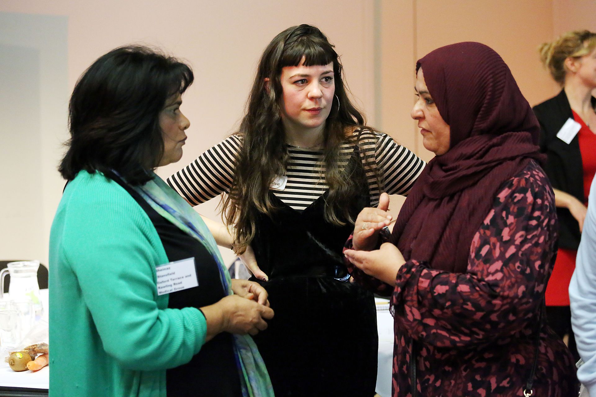 Three women are talking to each other in a room.