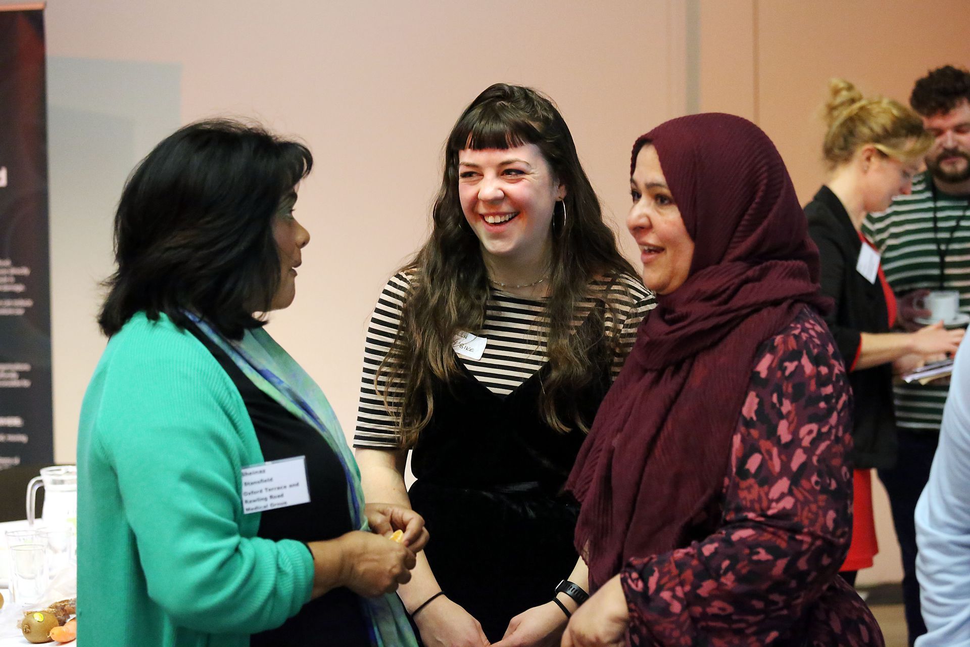Three women are talking to each other in a room.