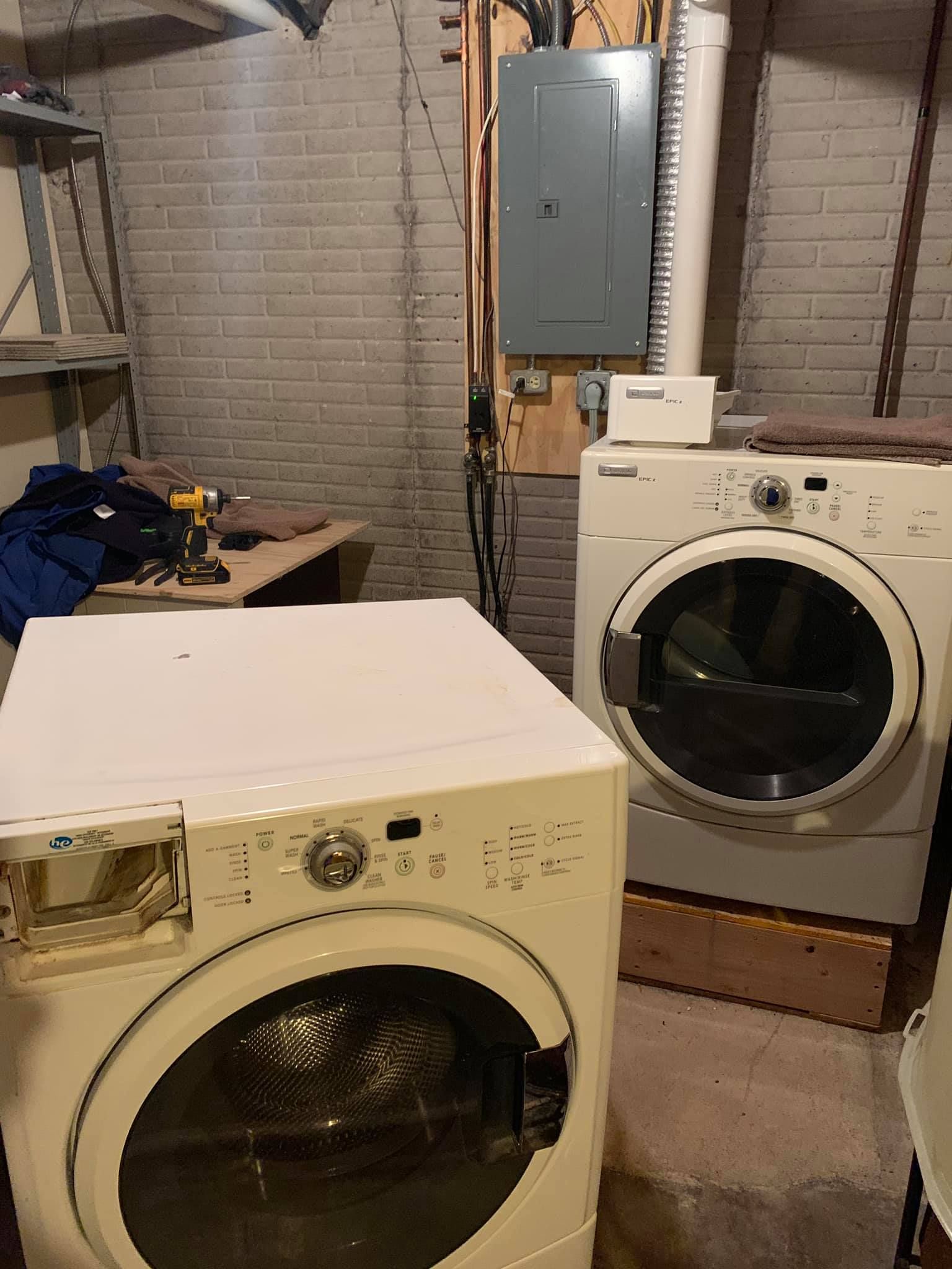 a washer and dryer are sitting next to each other in a basement .