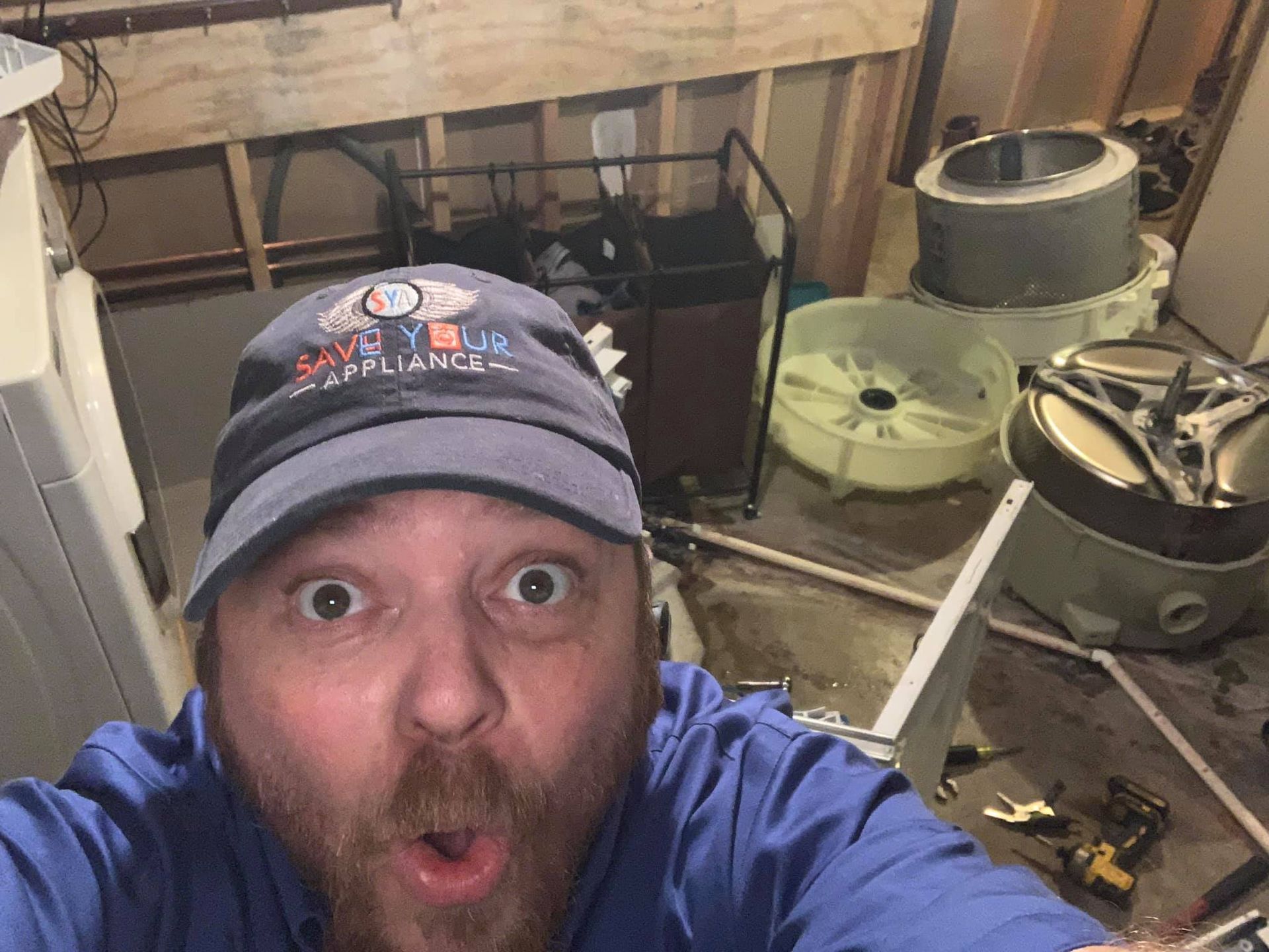 a man wearing a baseball cap is taking a selfie in a laundry room .