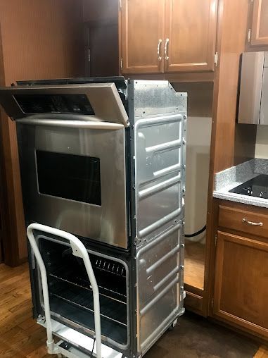 a stainless steel oven is sitting on a cart in a kitchen .